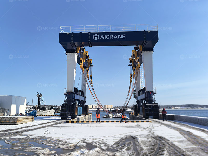 Marine travel lift lifting boat in winter harbor
